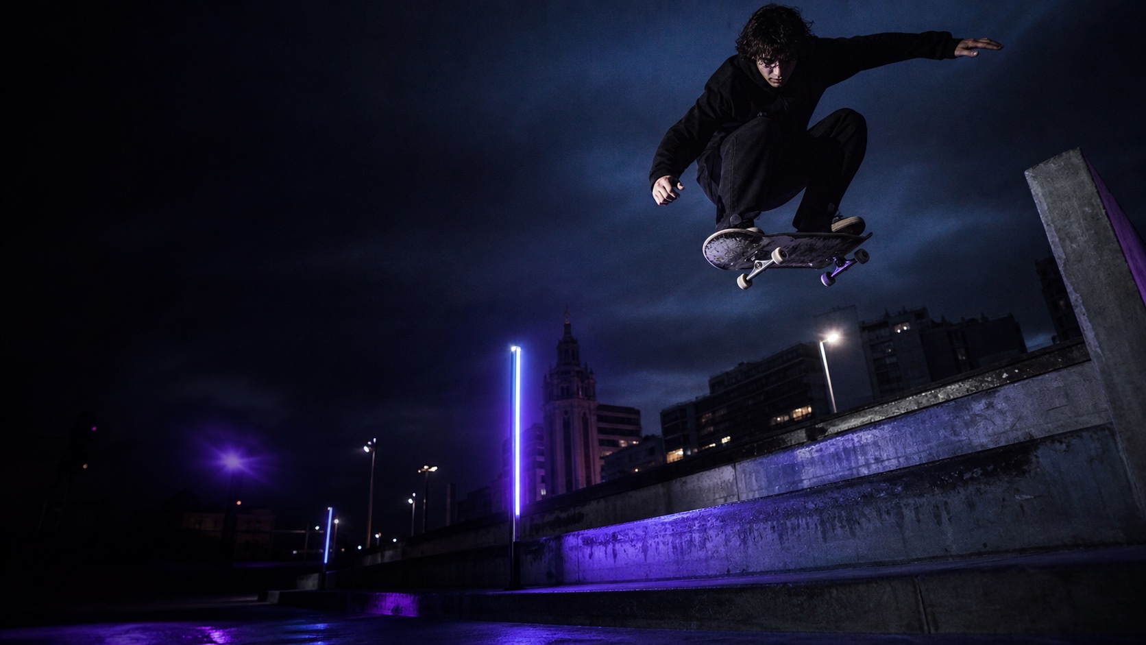 Persona haciendo un truco en skate sobre una plaza urbana de noche